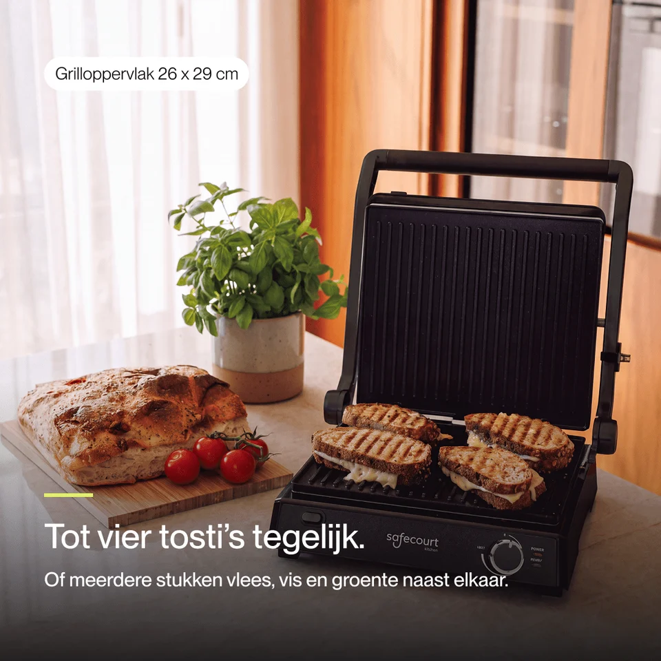 Un gril de contact ouvert avec quatre sandwiches grillés. À côté d'une miche de pain, de tomates et d'une plante.