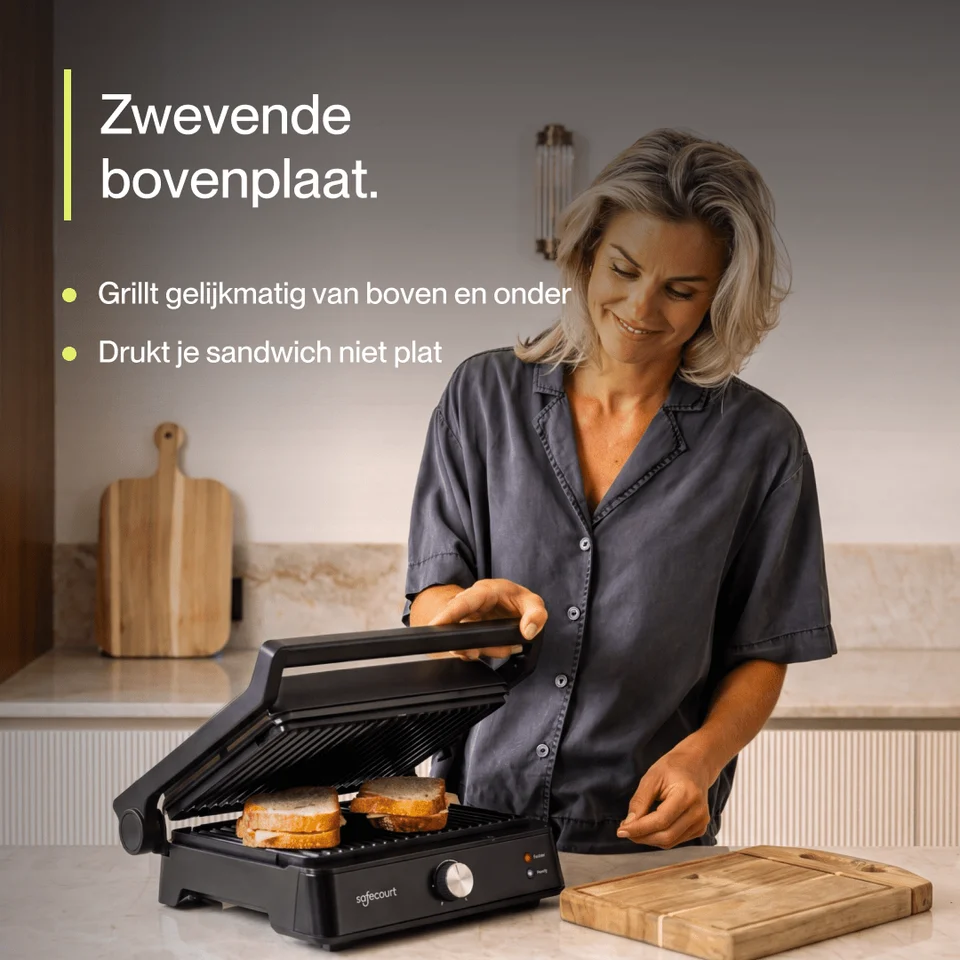 A woman in a kitchen prepares sandwiches using an electric grill.