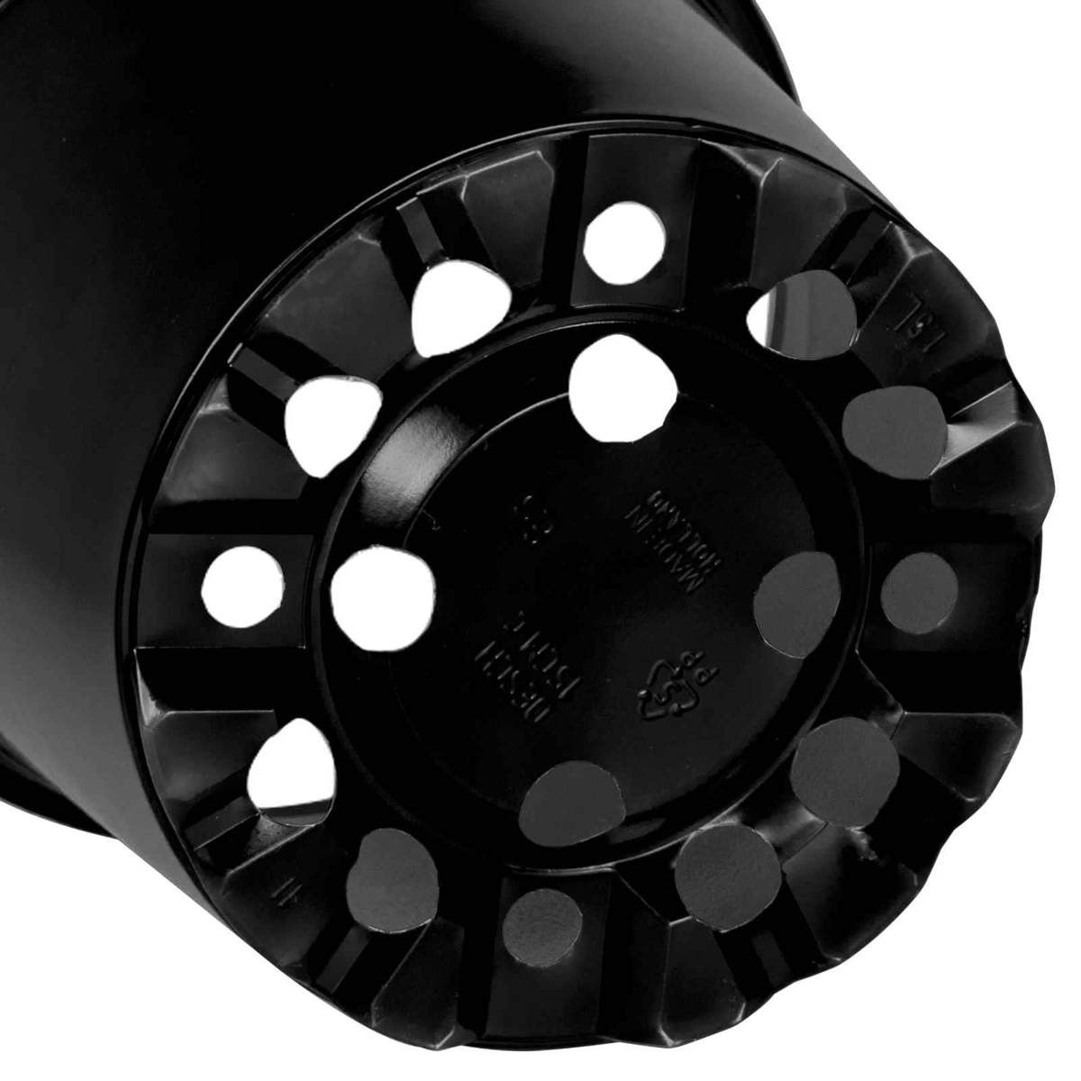 Die Unterseite eines schwarzen Plastikblumentopfs mit zahlreichen Entwässerungslöchern.