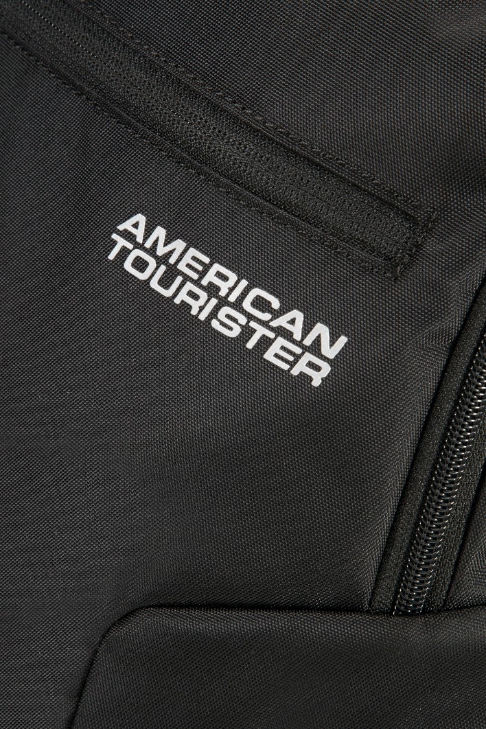 Close-up van een zwarte American Tourister rugzak met wit logo en ritsen.