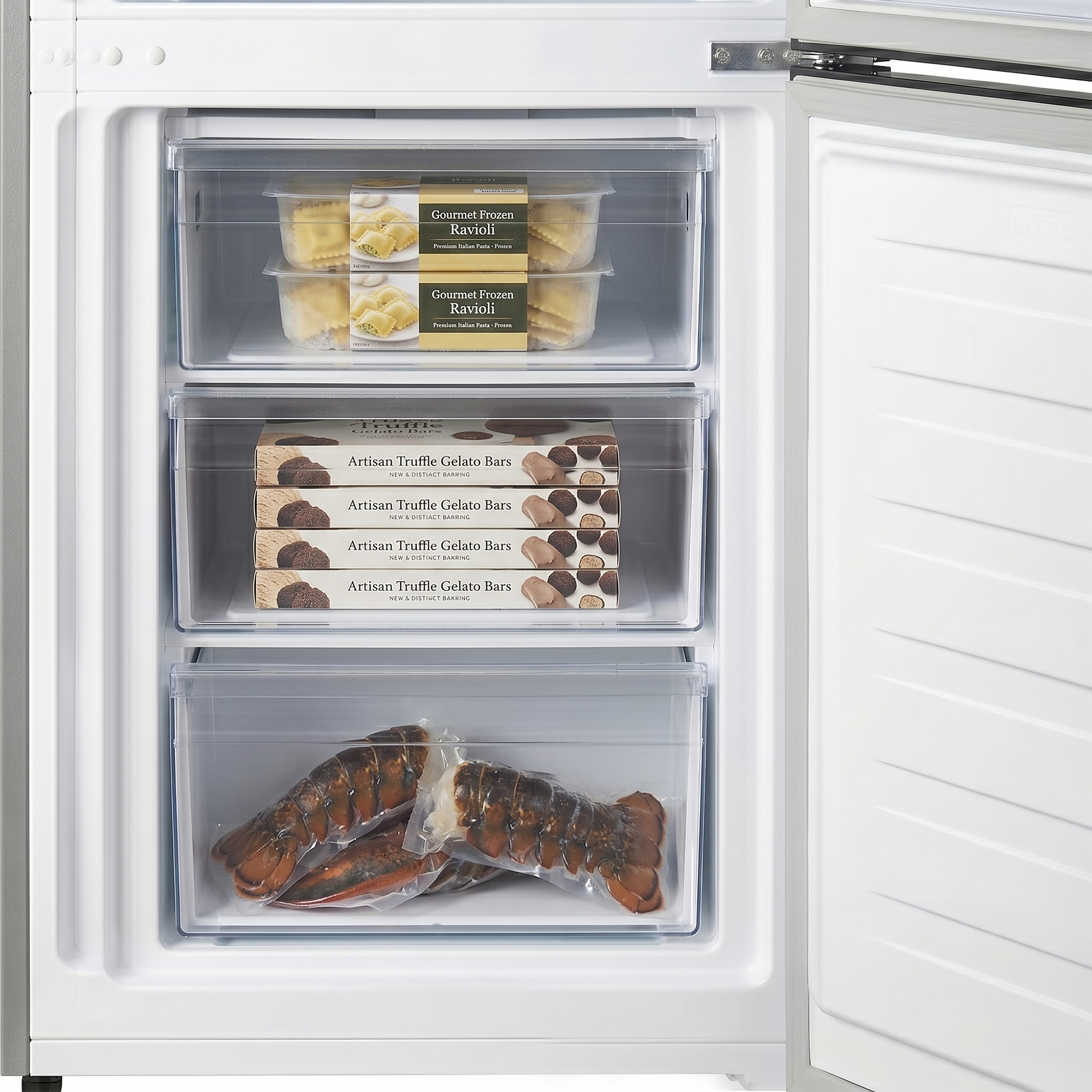 An open freezer with three drawers contains frozen ravioli, gelato bars, and vacuum-sealed lobster tails.