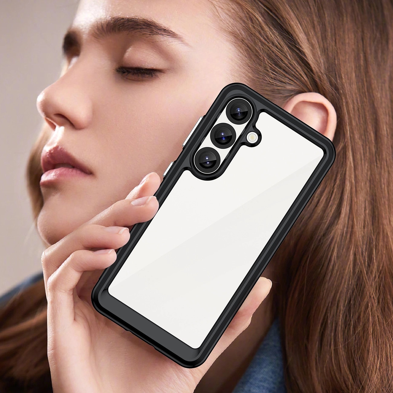 Una donna tiene vicino al viso uno smartphone con cornice nera e retro trasparente.