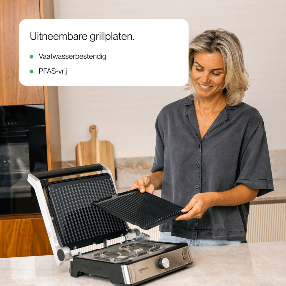 A woman in a kitchen demonstrates removable grill plates of a contact grill.