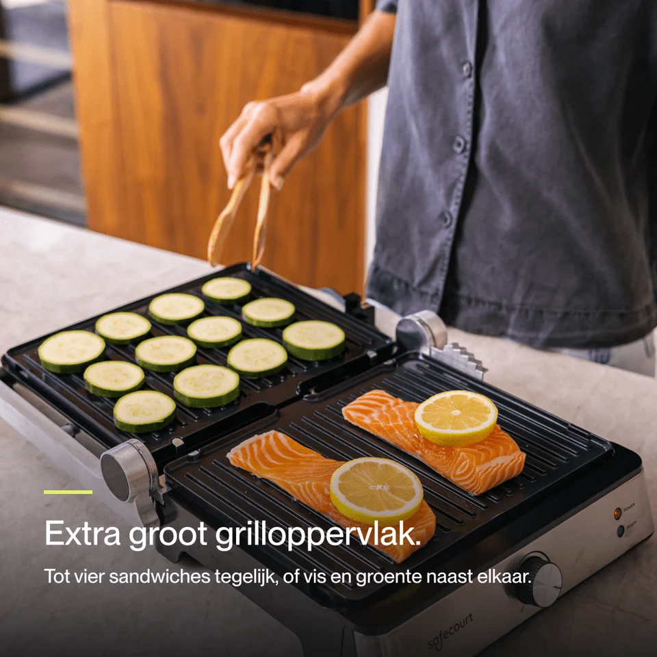 A person grills zucchini slices and salmon fillets with lemon on a large electric tabletop grill.