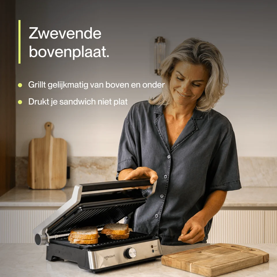 A woman in a kitchen lifting the top plate of a sandwich maker with grilled sandwiches inside.