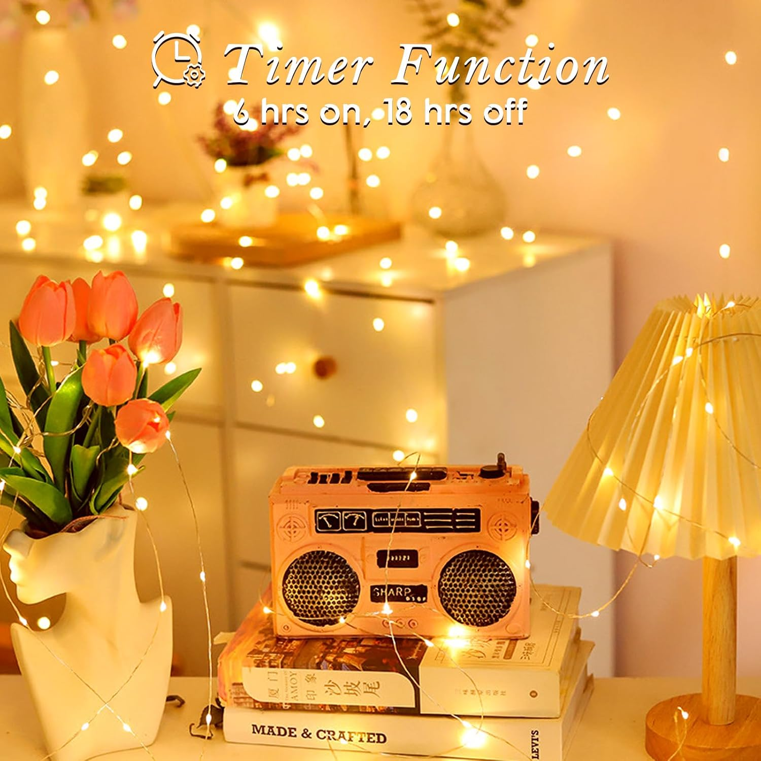Eine rosa Ghettoblaster auf Büchern, neben orangefarbenen Tulpen und einer Lampe, umgeben von warmen Lichterketten.