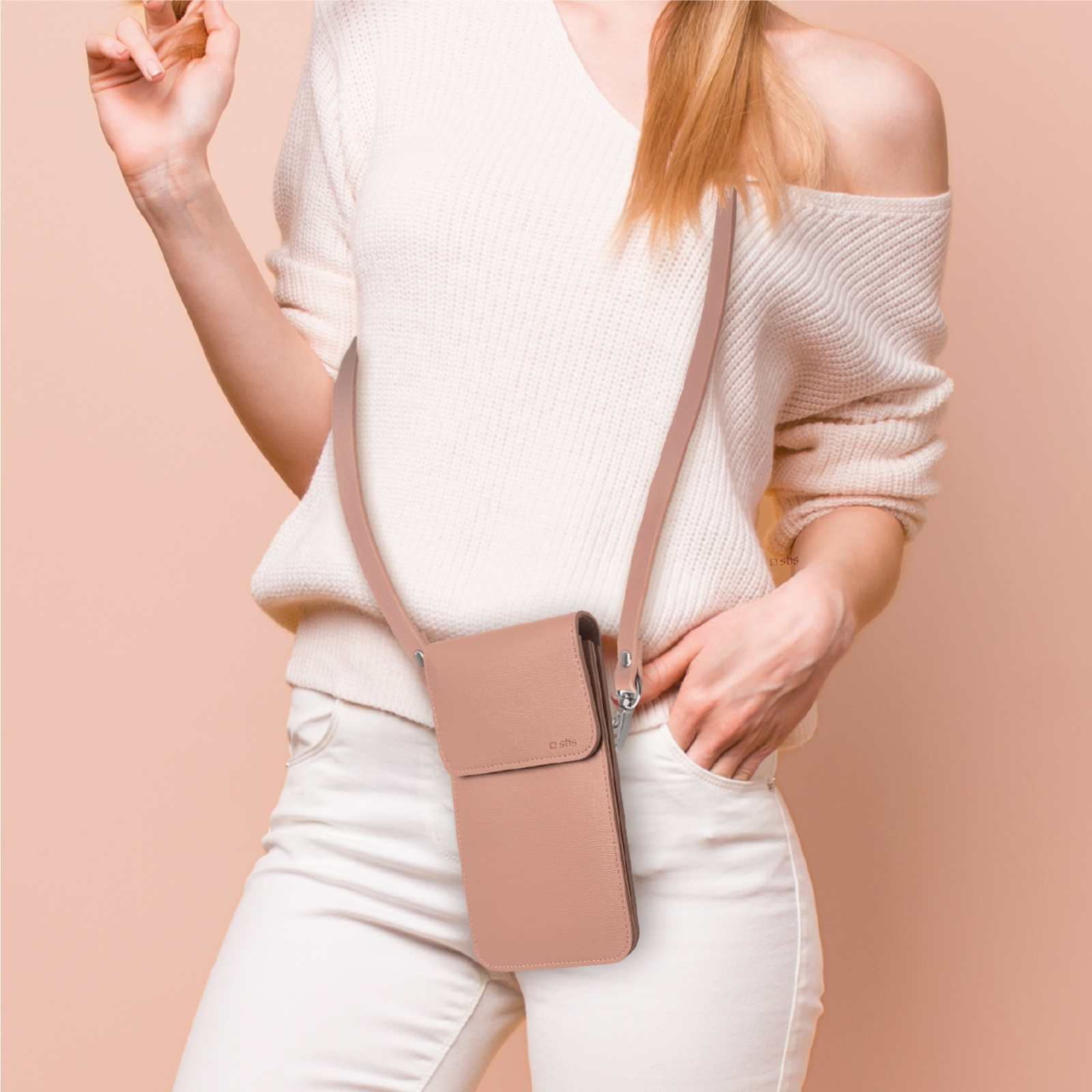 Una donna con maglione bianco e pantaloni bianchi indossa una piccola borsa a tracolla rosa.