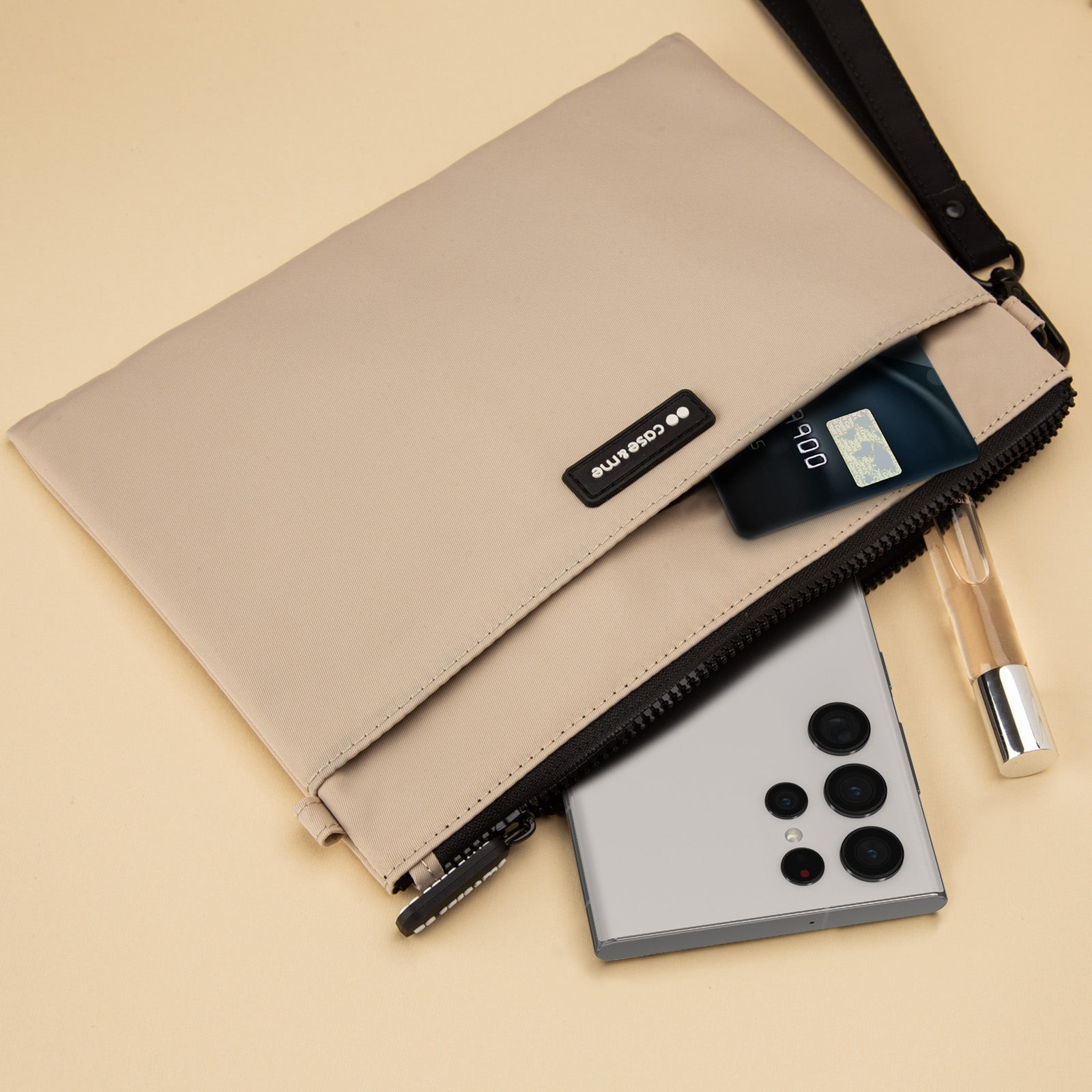 Bolso beige con smartphone, tarjeta de crédito y perfume sobre fondo claro.