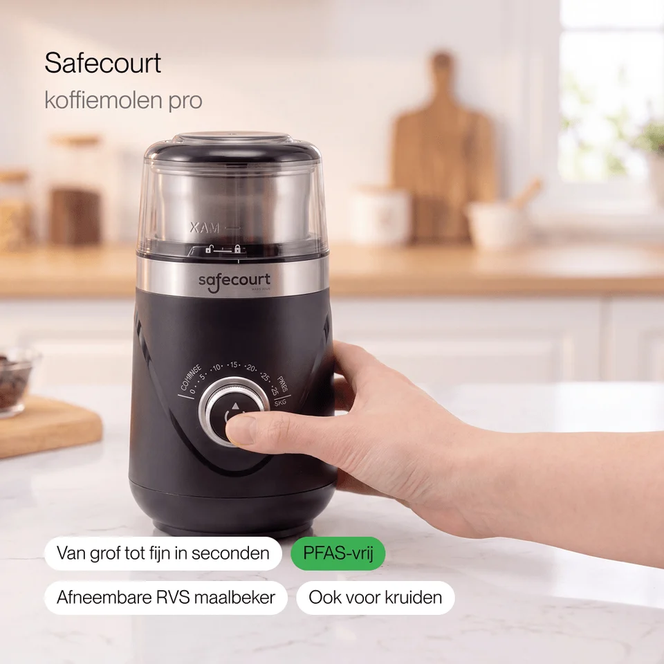 A hand turns the dial on a black Safecourt coffee grinder in a kitchen.