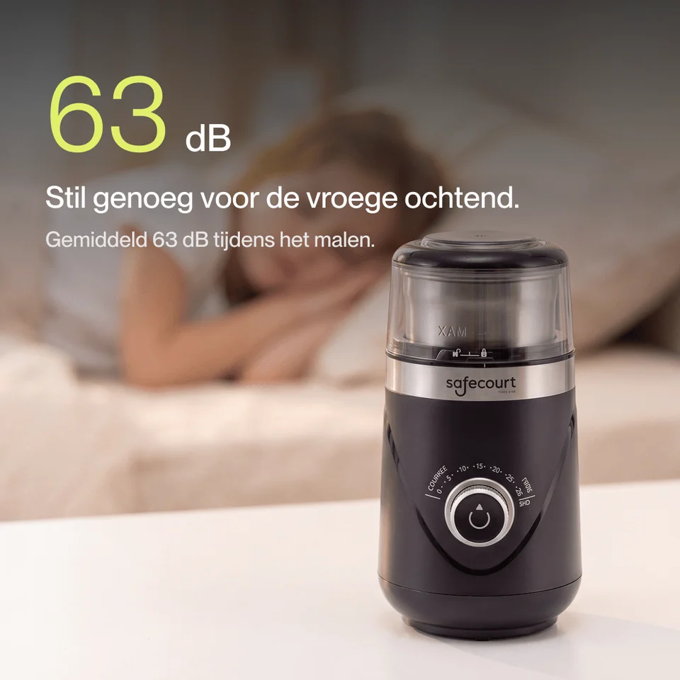 Black coffee grinder on a white table in front of a sleeping woman.