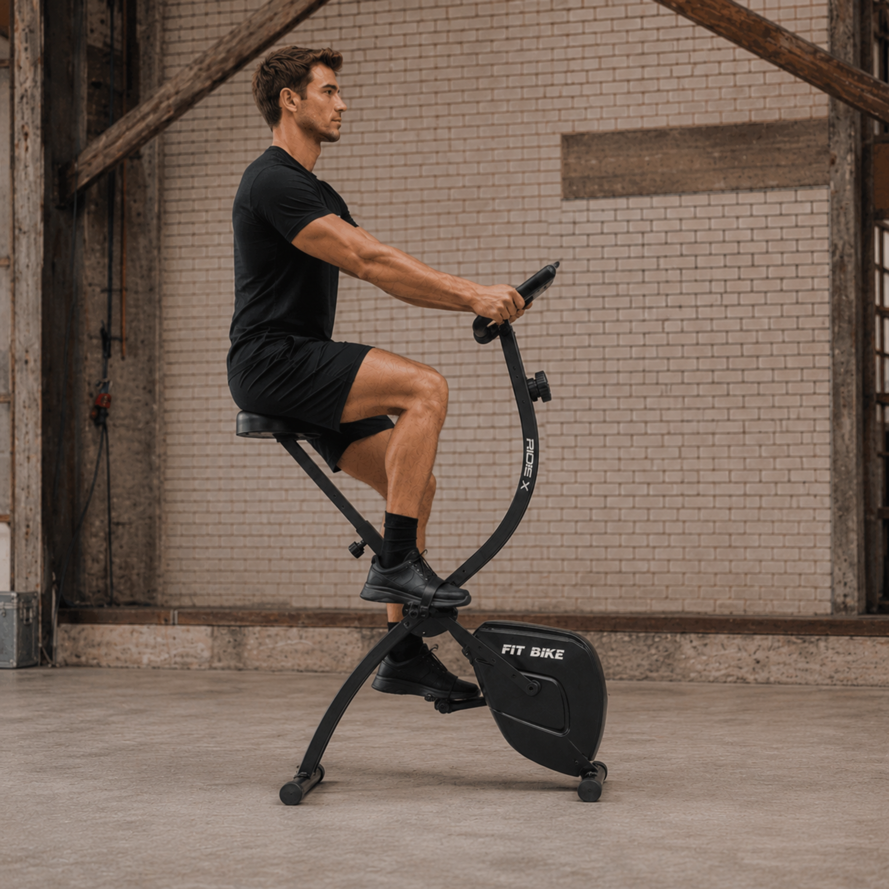 Een man in zwarte sportkleding fietst op een zwarte hometrainer in een gym.