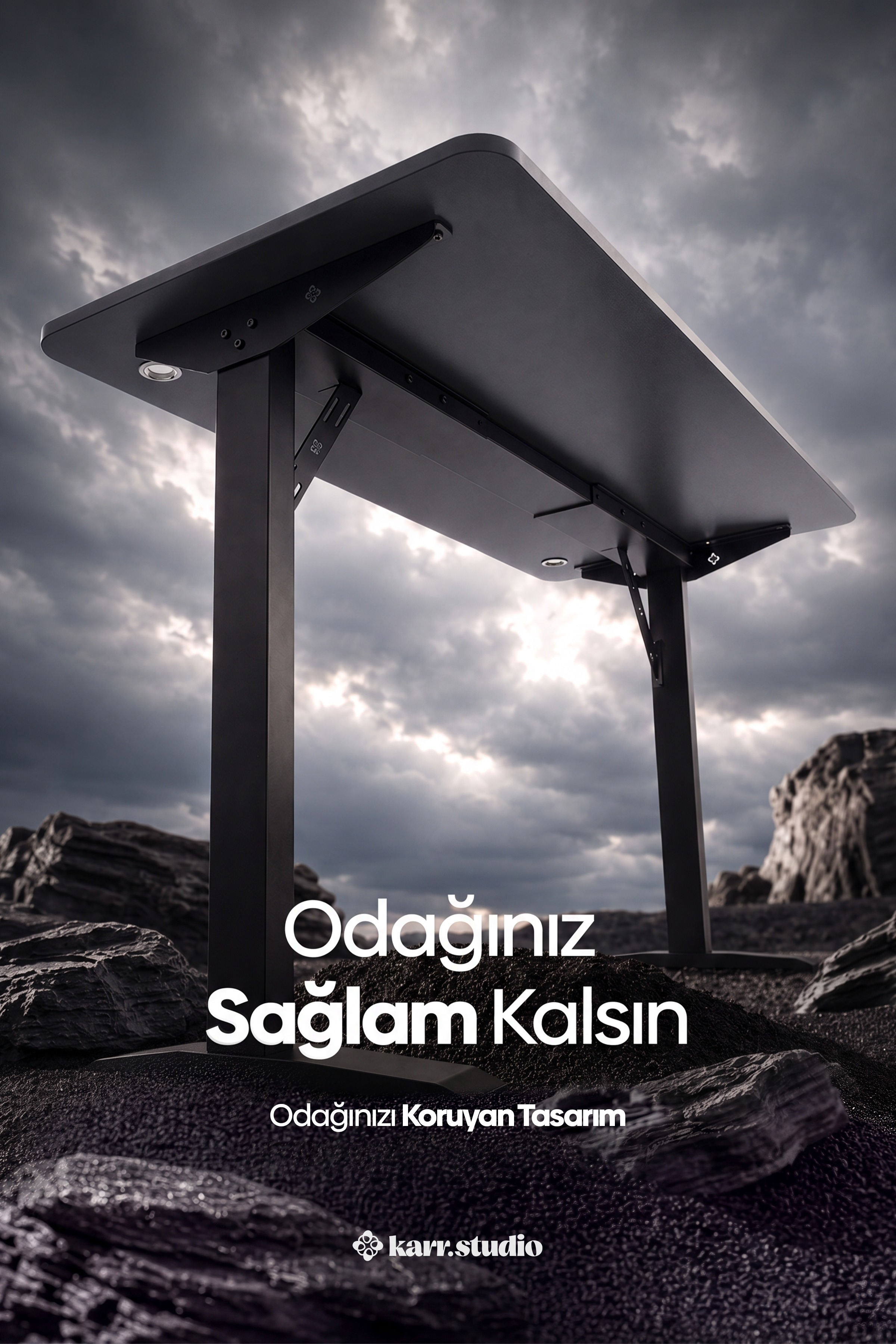 Bulutlu bir gökyüzü altında kayalık zeminde duran siyah bir çalışma masası.