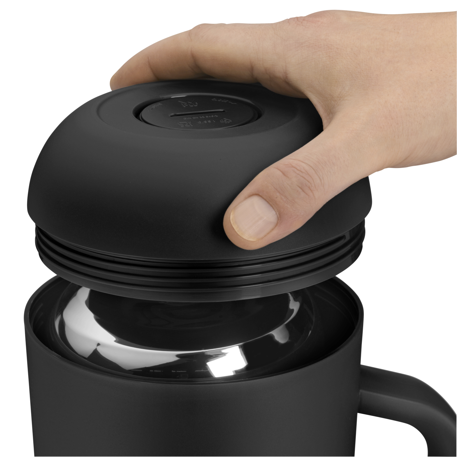 Une main ouvre le couvercle d'un thermos noir, révélant un intérieur argenté brillant.