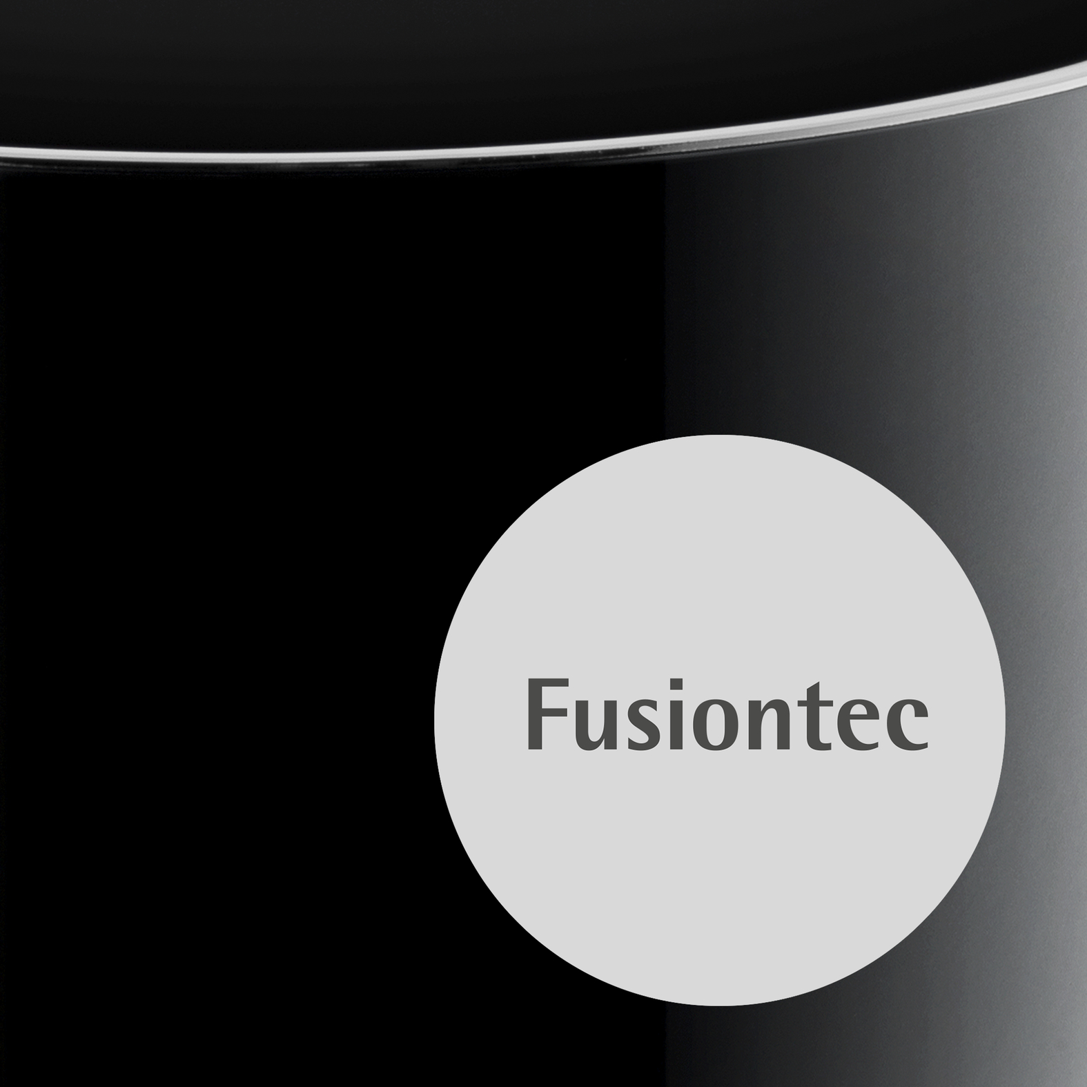 Ein runder, weißer Aufkleber mit dem Text 'Fusiontec' auf einem glänzenden schwarzen Untergrund.