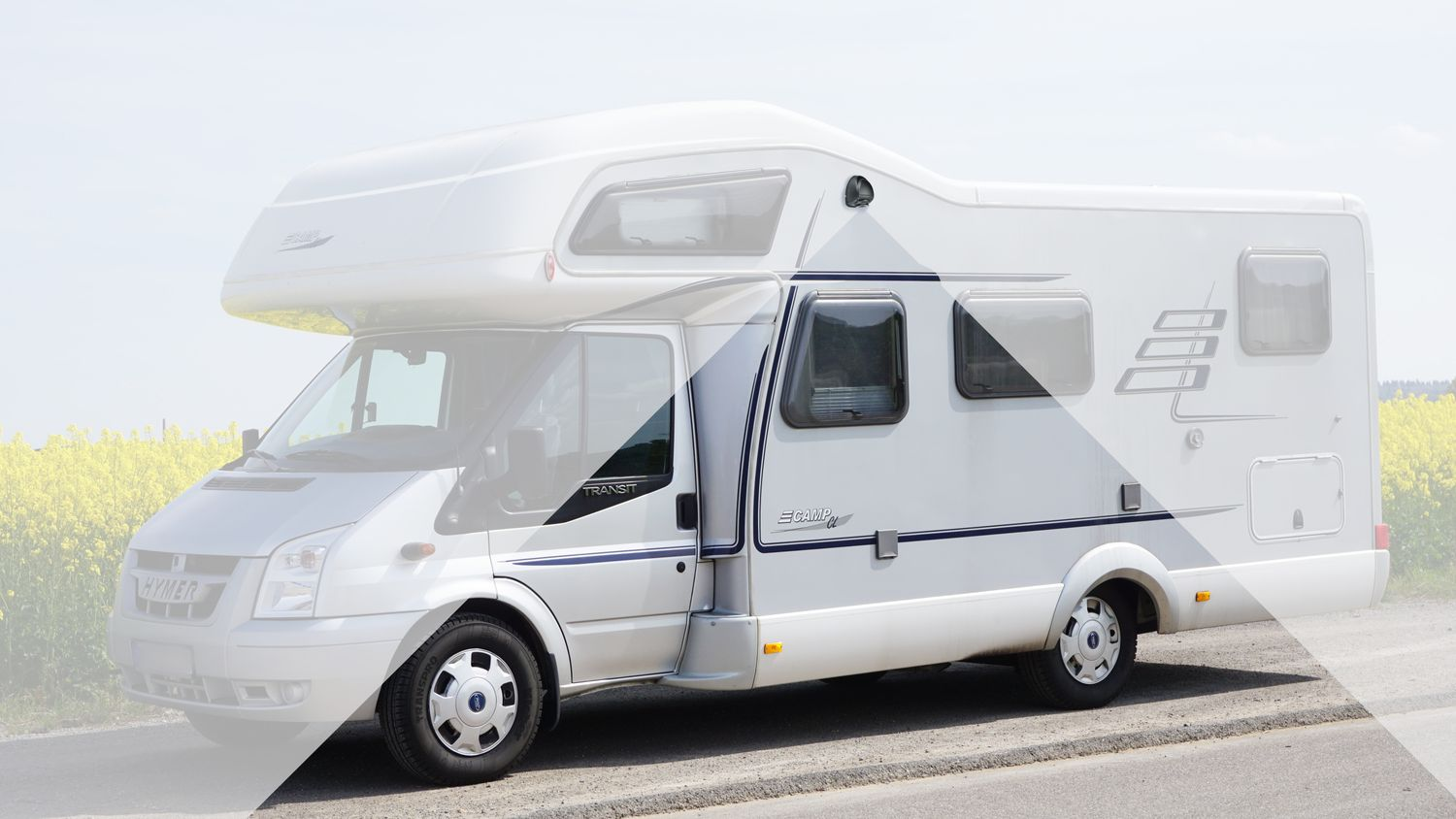 Ein weißes Wohnmobil, das am Straßenrand geparkt ist, mit einem Feld im Hintergrund.
