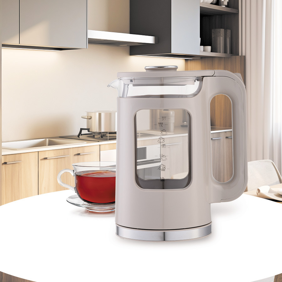 Un bollitore in vetro beige e una tazza di tè sono su un tavolo bianco in una cucina moderna.