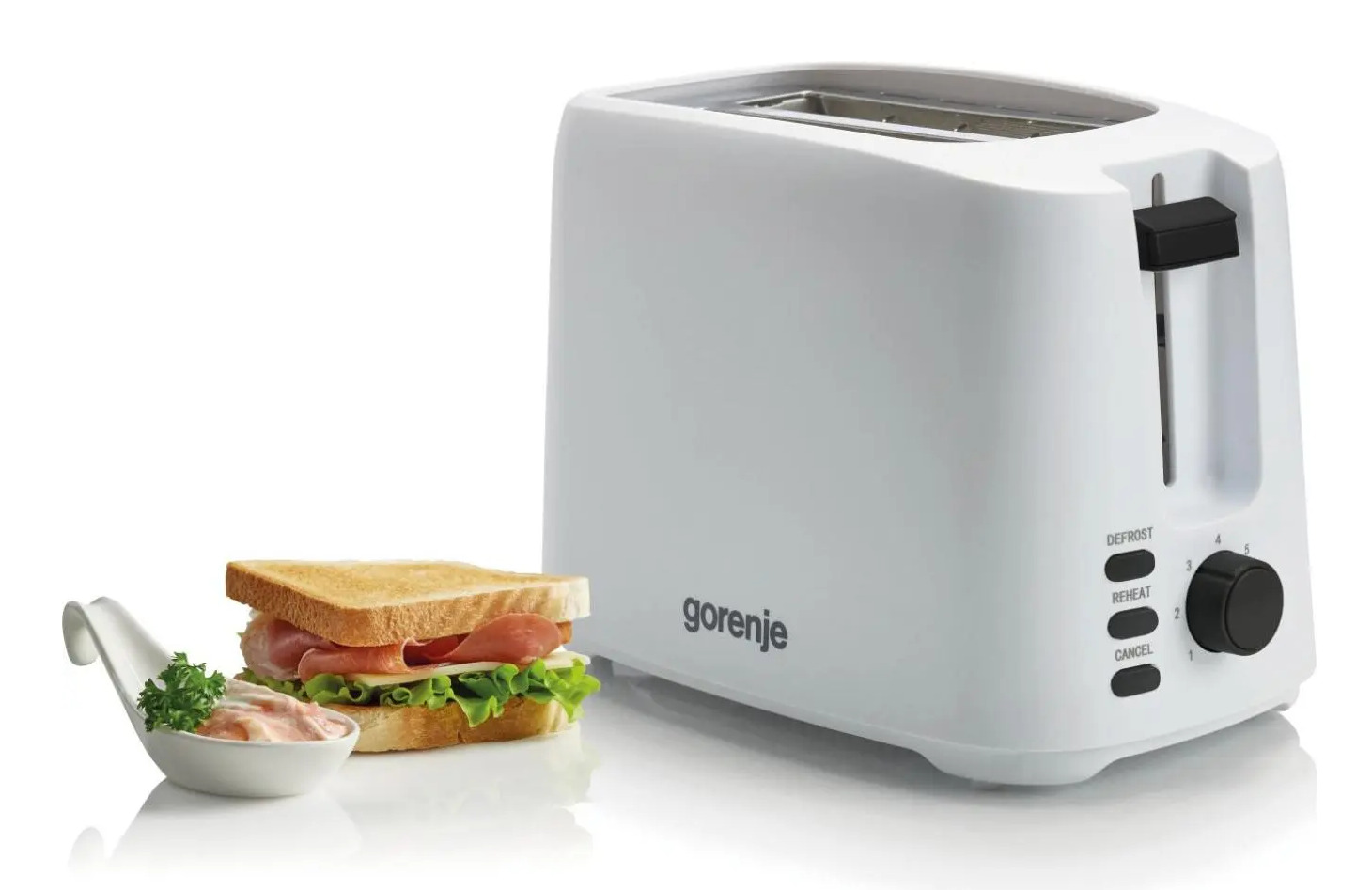 Un tostapane bianco Gorenje è accanto a un tramezzino e una ciotolina di salsa su una superficie bianca.