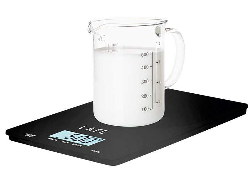 Ein Glas Messbecher mit Milch steht auf einer schwarzen Lafe Küchenwaage, die 500 Gramm anzeigt.