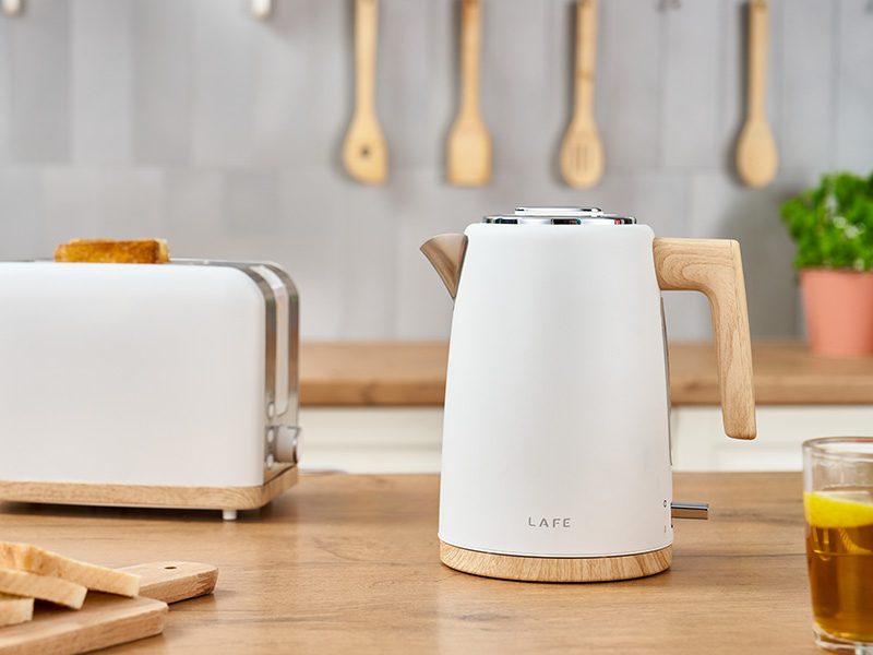 Un bollitore elettrico bianco con dettagli in legno su un piano di lavoro.
