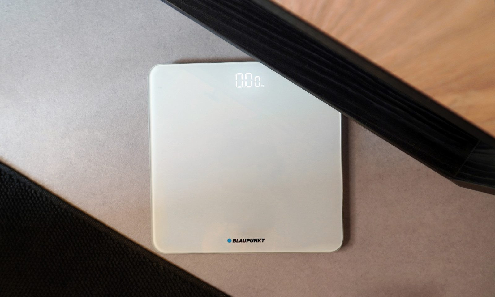 Eine weiße Blaupunkt Personenwaage auf grauem Boden, die 0,00 kg anzeigt.