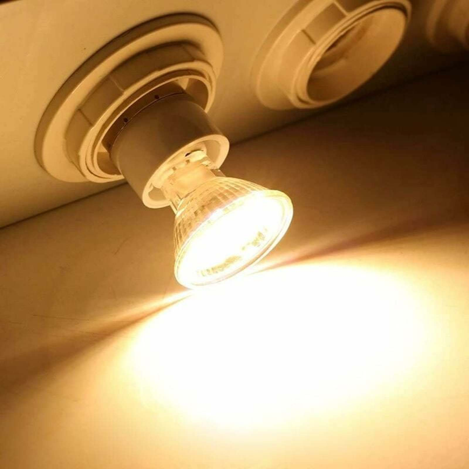 Ein eingeschalteter Halogenspot ist an einer weißen Decke montiert und strahlt warm.