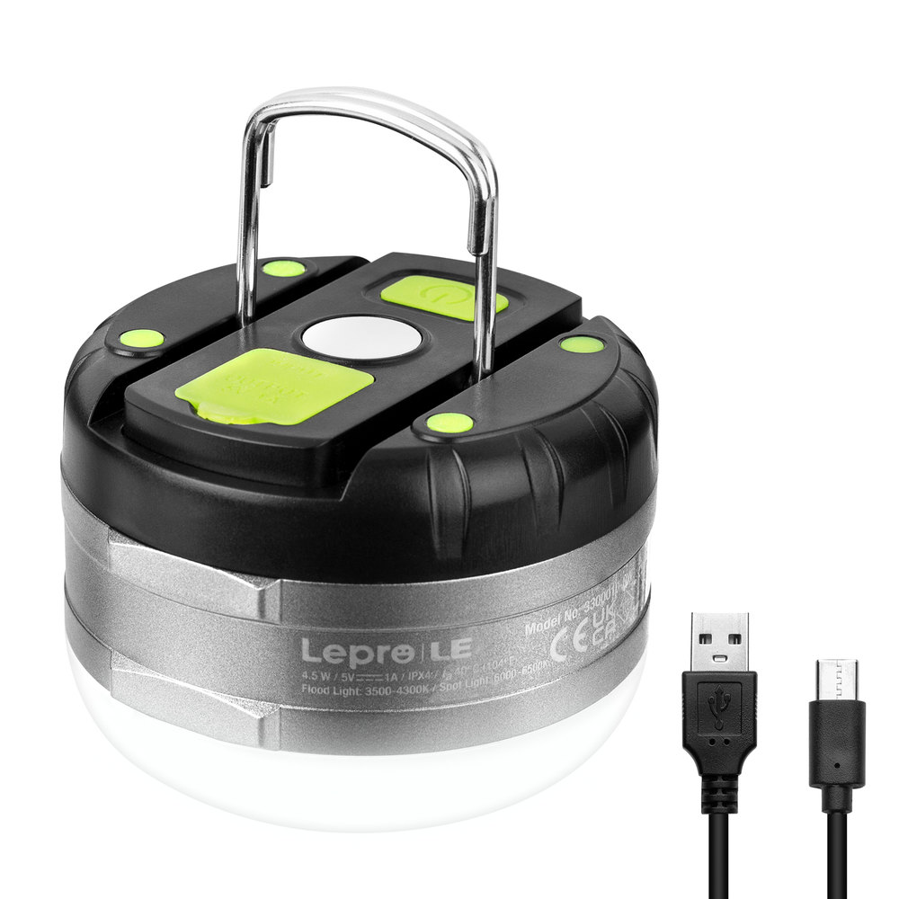 Eine kompakte runde LED-Campinglampe in Schwarz und Silber mit Metallgriff und einem USB-Ladekabel daneben.