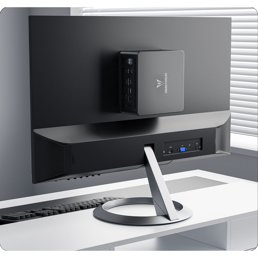 Un mini PC Minisforum è fissato sul retro di un monitor su una scrivania bianca.