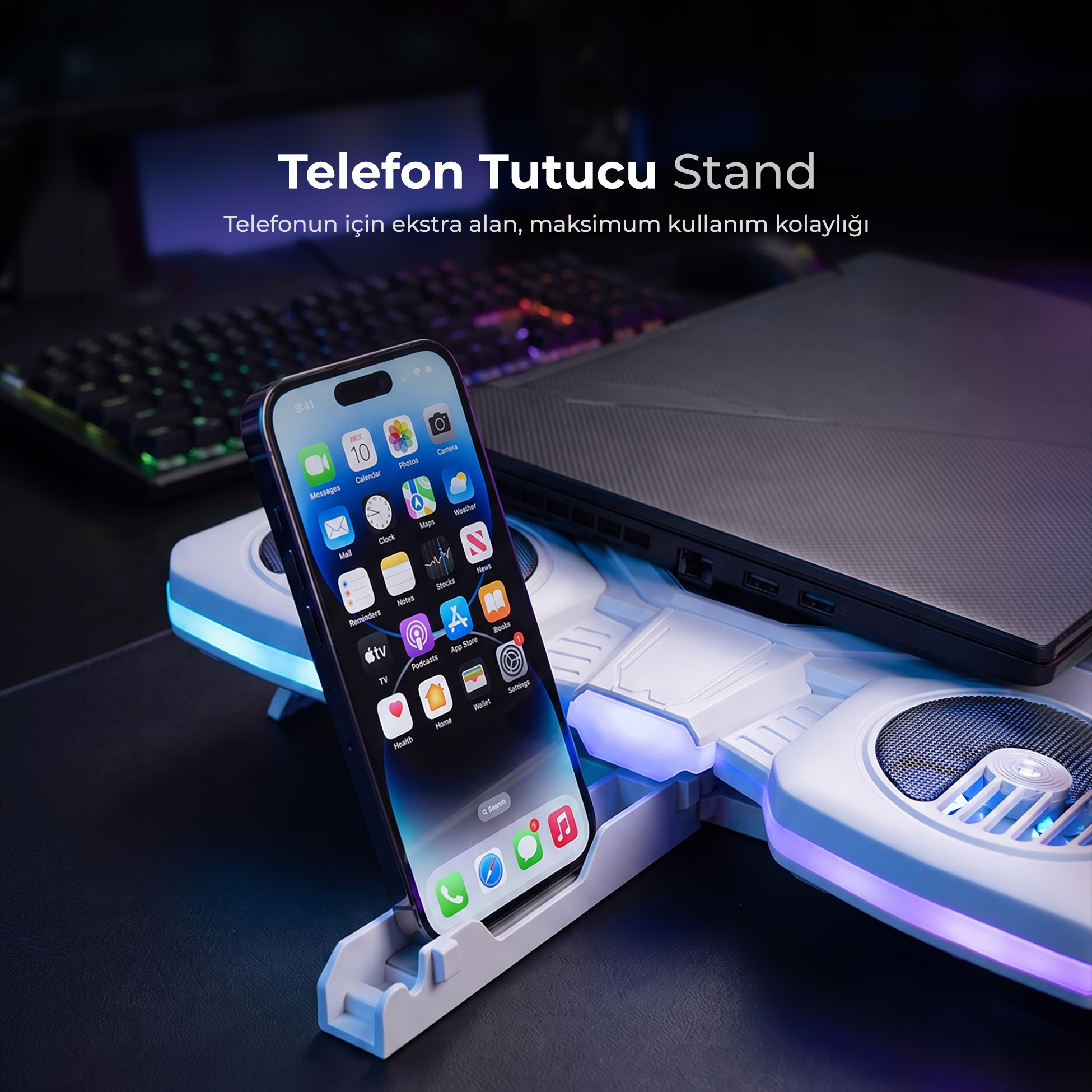 Dizüstü bilgisayar ve klavyenin yanında, ışıklı stantta duran bir akıllı telefon.