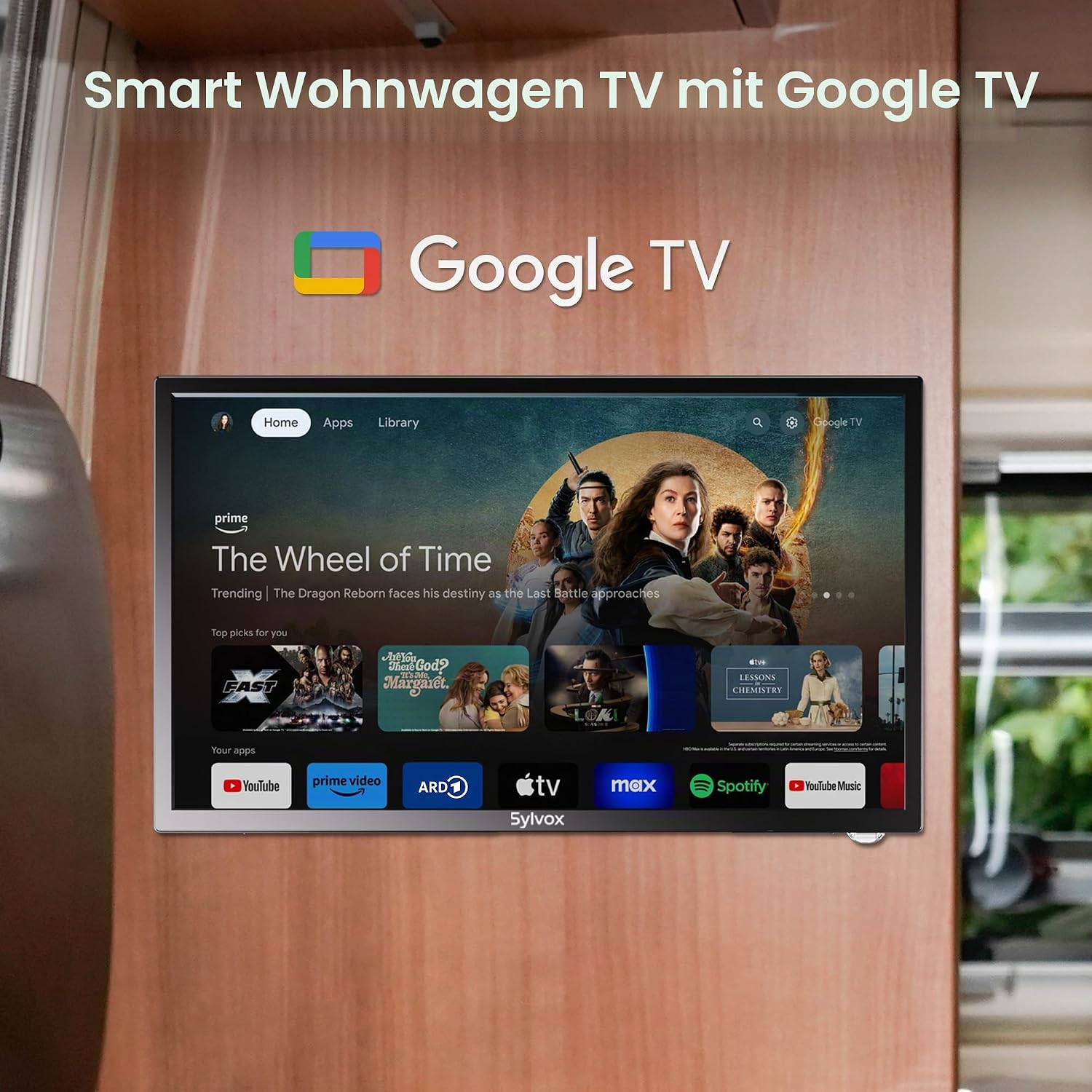 Ein Wohnwagen-Fernseher mit Google TV zeigt die Benutzeroberfläche und die App-Auswahl vor einer Holztafel.