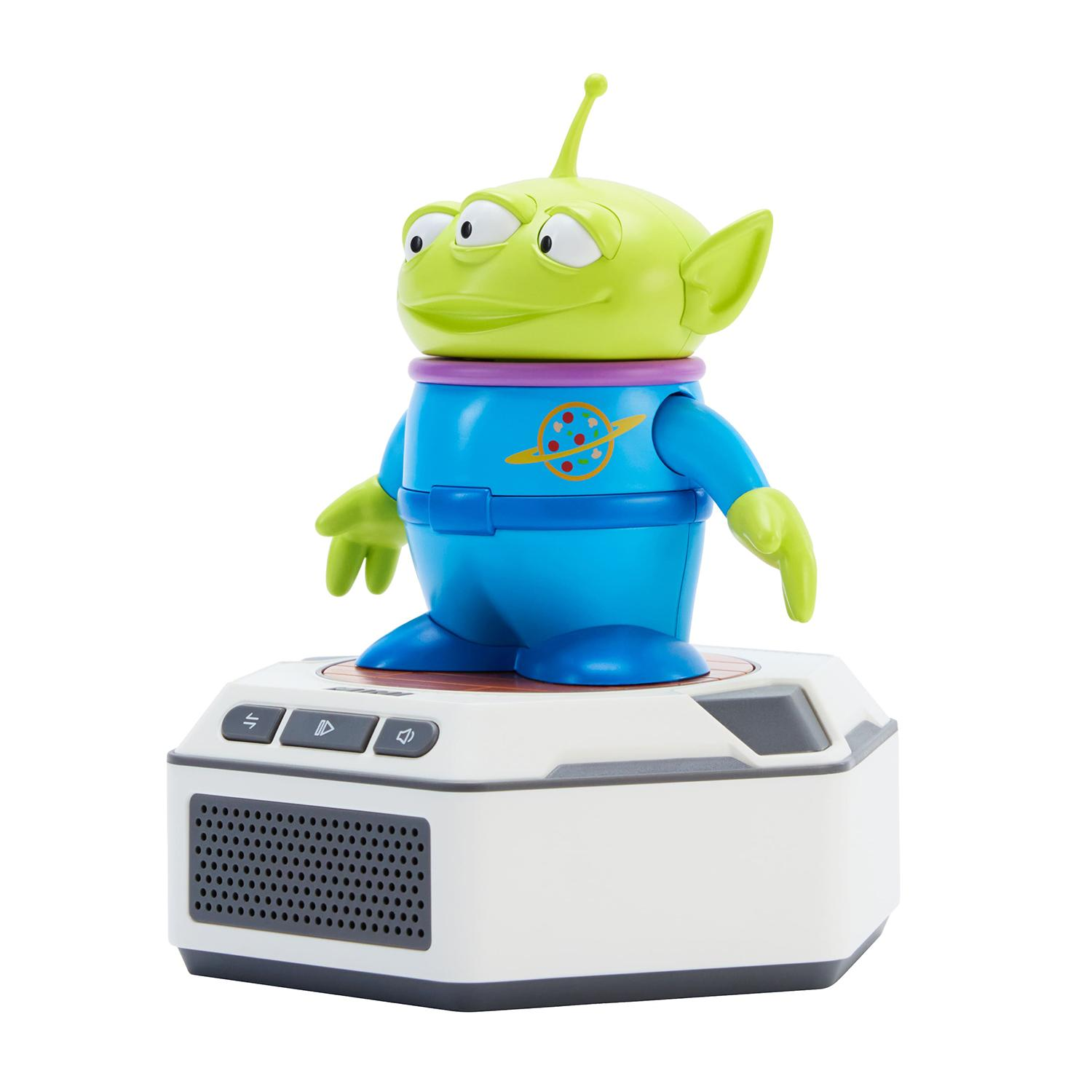 Un alienígena verde de Toy Story se para en una base de altavoz hexagonal blanca con tres botones.