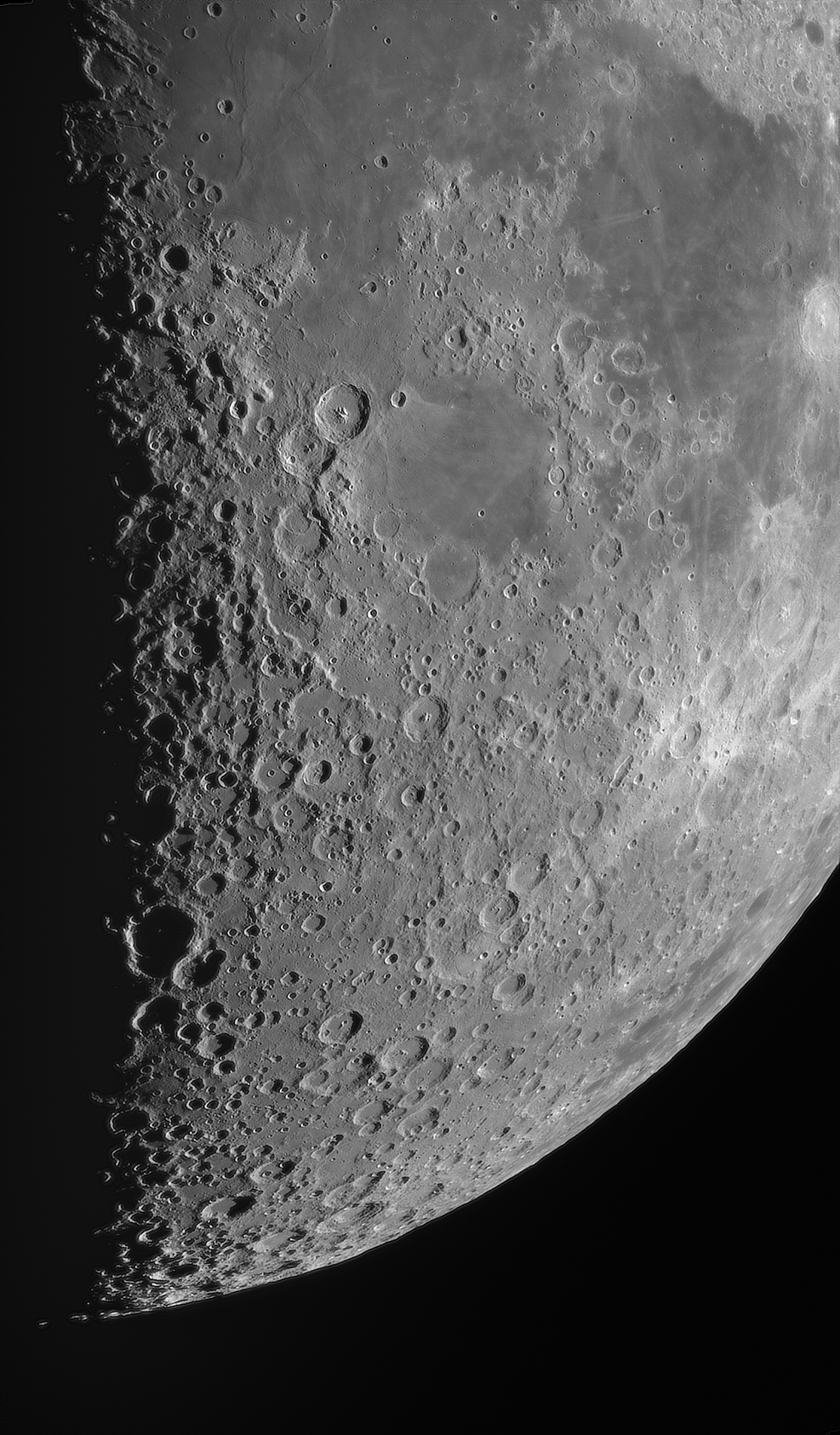 Primer plano de la superficie lunar con cráteres y mares oscuros contra el espacio negro.