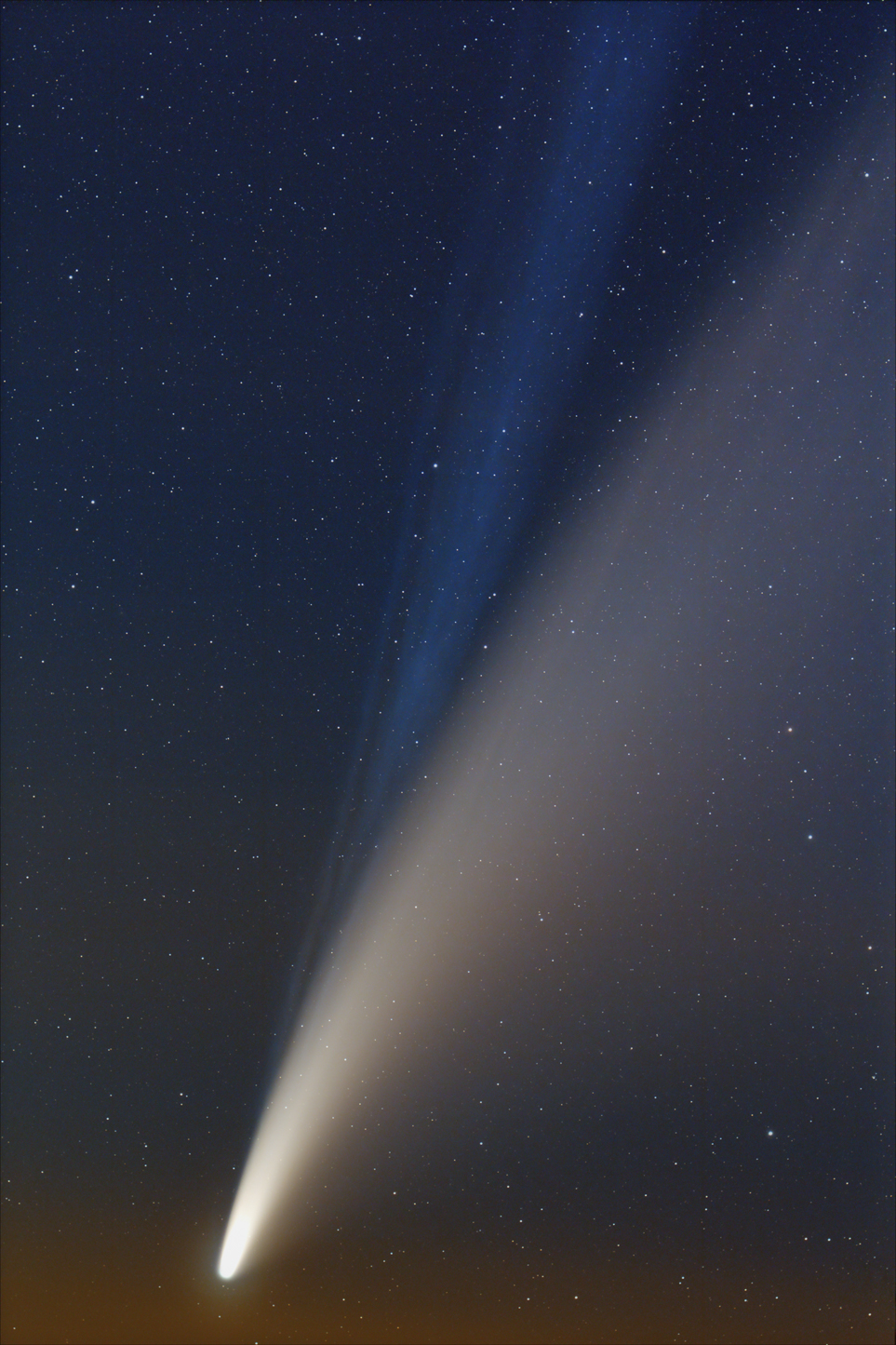 Un cometa con una brillante cola blanca y azul brilla en el cielo nocturno estrellado.