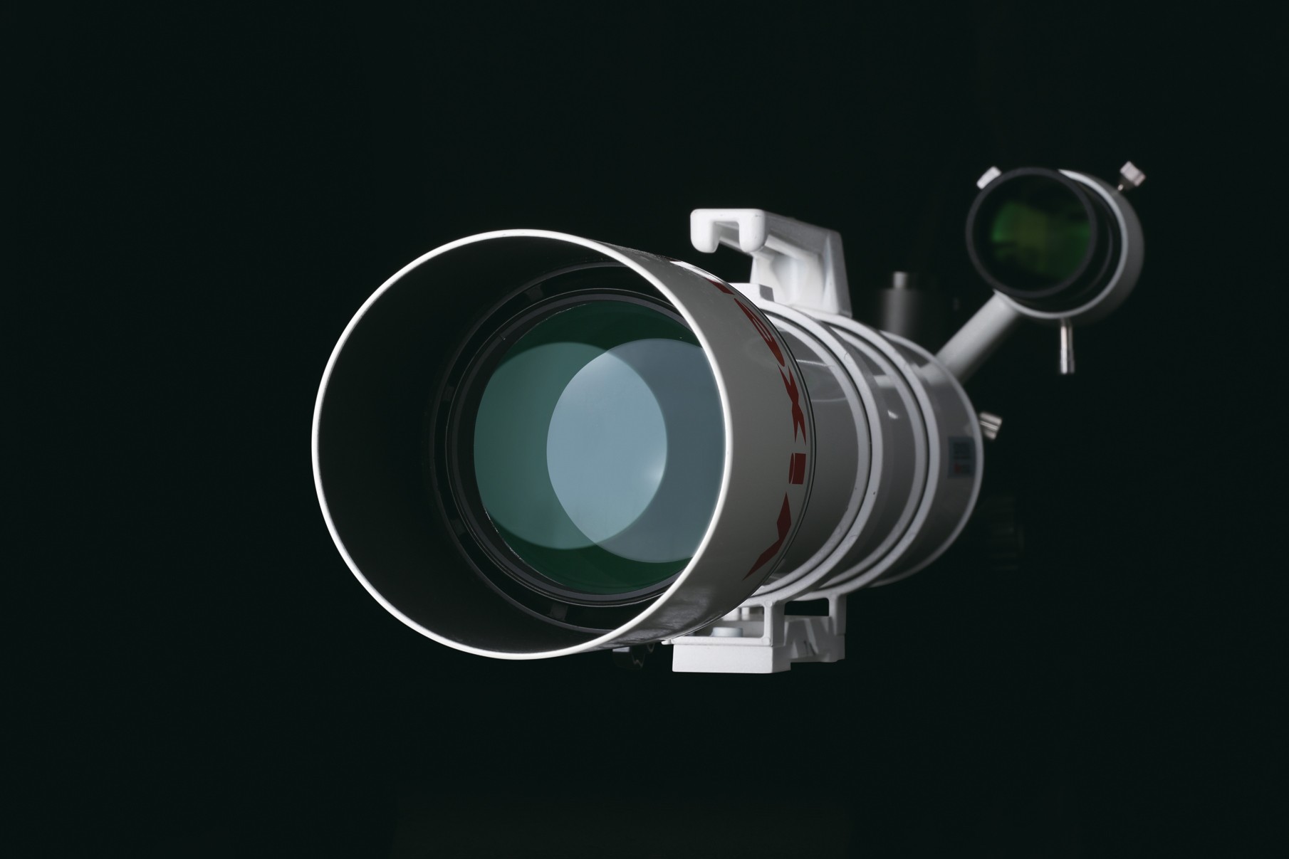 Un telescopio astronómico blanco con una lente verde sobre fondo negro.