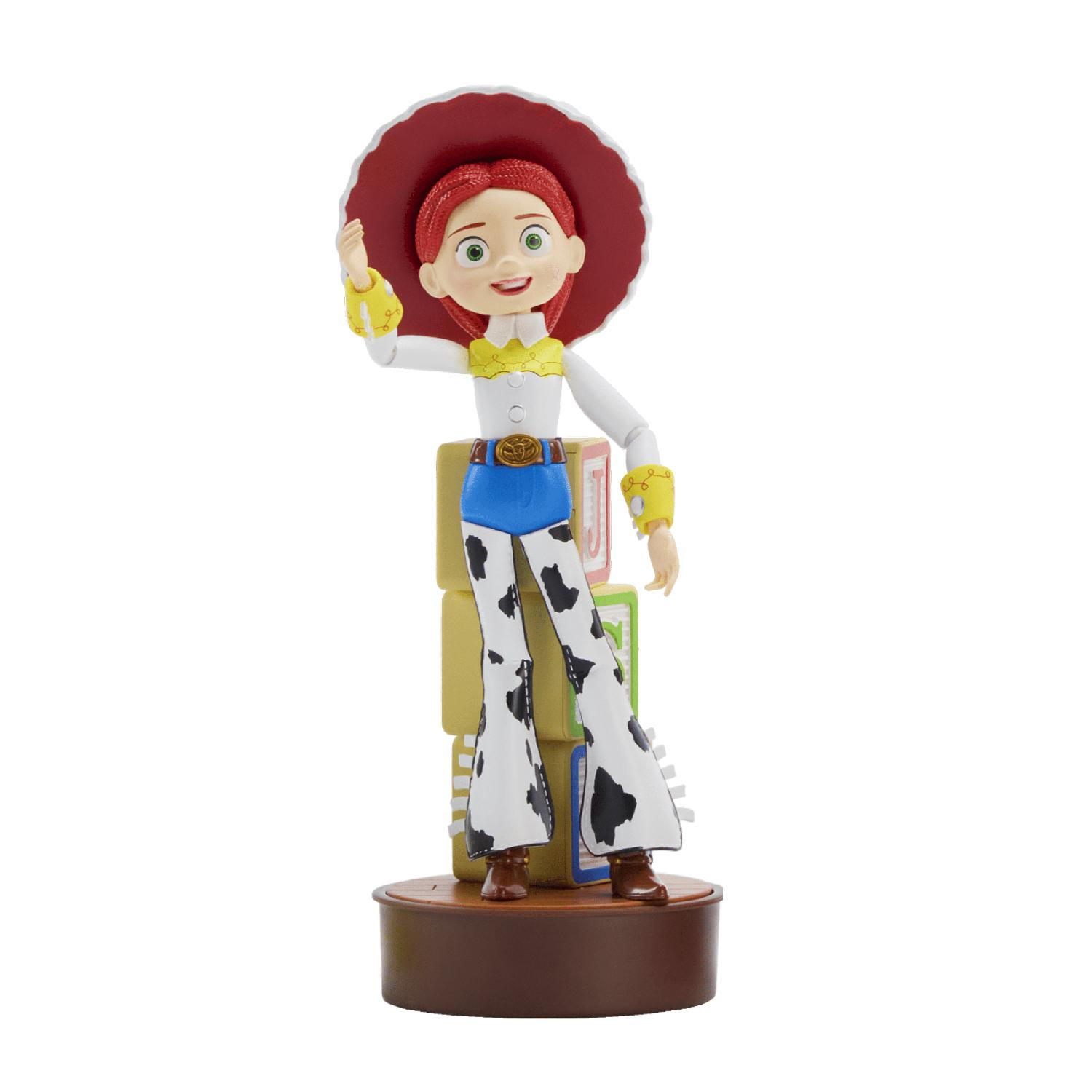 Una figura de Jessie de Toy Story de pie frente a bloques de letras en una base marrón, saludando con la mano derecha.