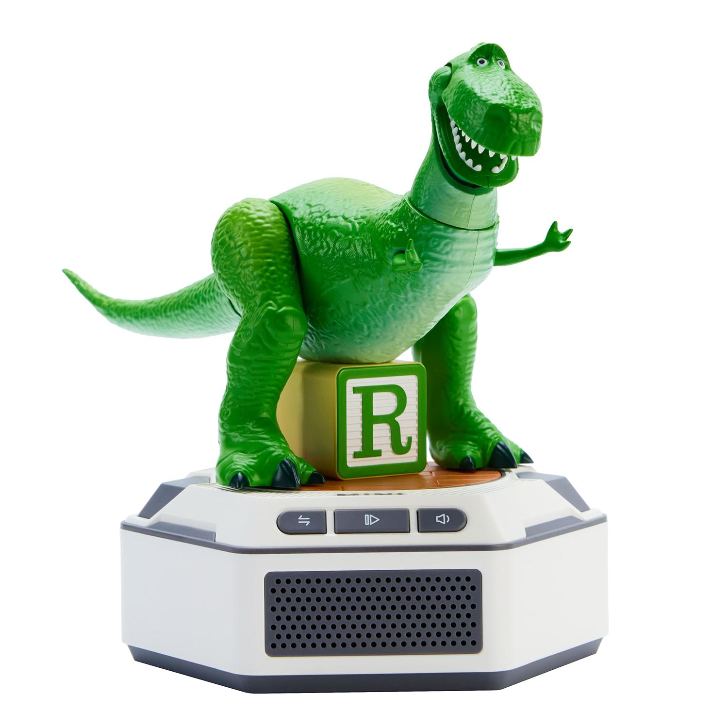 Un dinosaurio de juguete verde sobre un bloque con la letra R encima de una base electrónica.