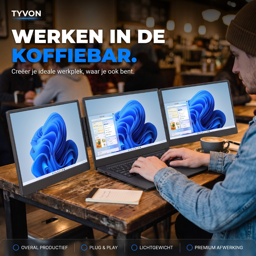 Een man werkt in een koffiebar op een laptop met drie schermen.
