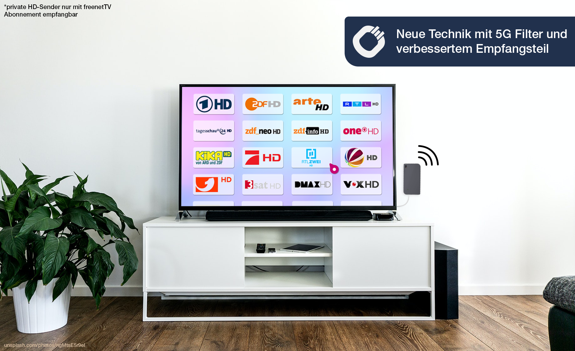 Ein Fernseher zeigt verschiedene HD-Senderlogos, ein kleiner Antennen-Empfänger steht daneben.
