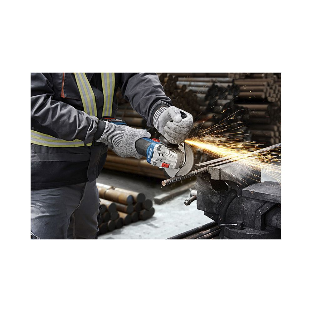 Un lavoratore con guanti protettivi e gilet riflettente taglia barre metalliche con una smerigliatrice, producendo scintille.