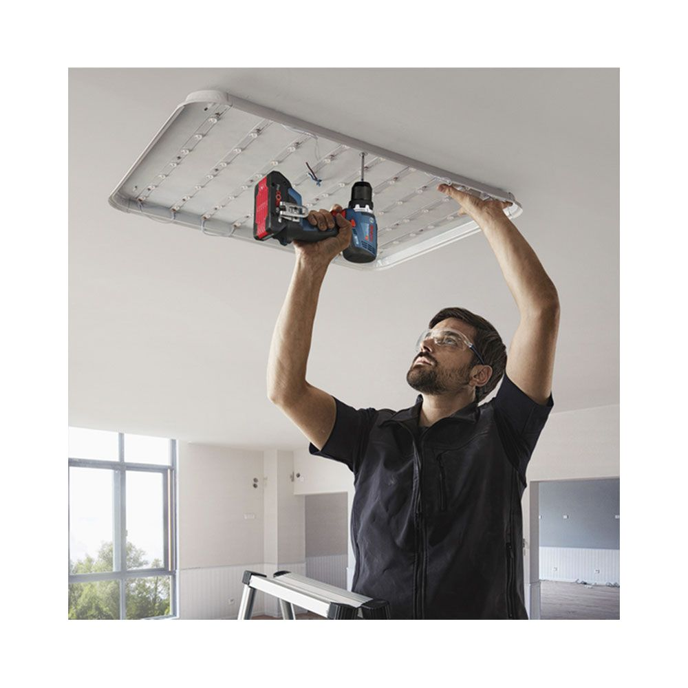Un operaio che fora una lampada da soffitto.