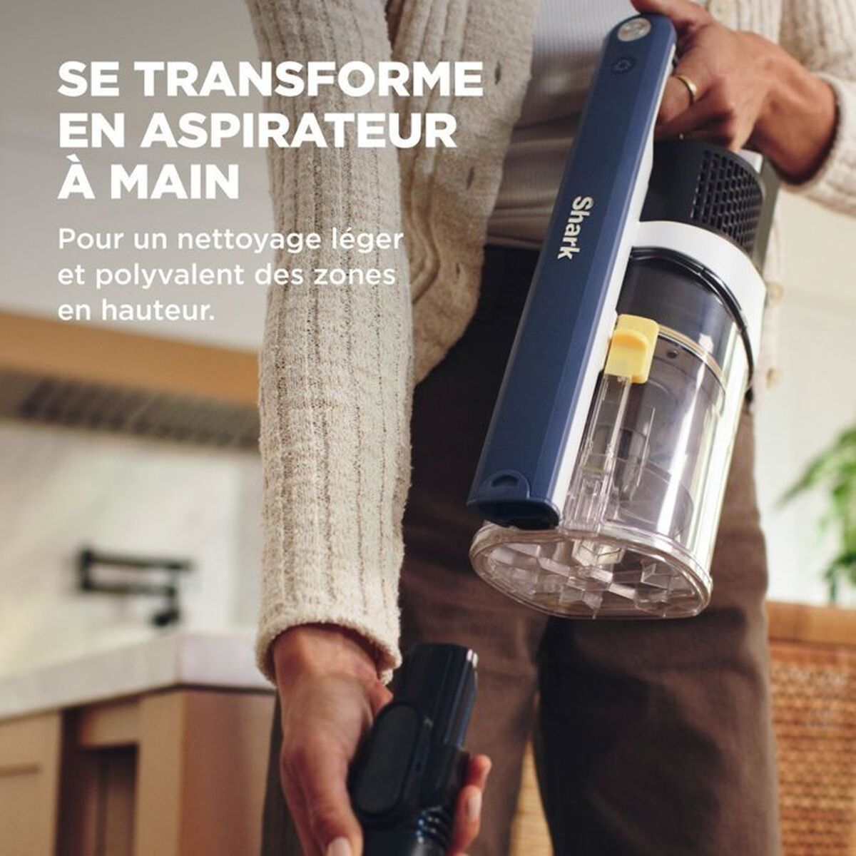 Persona che tiene un aspirapolvere portatile Shark blu, con testo pubblicitario in francese.