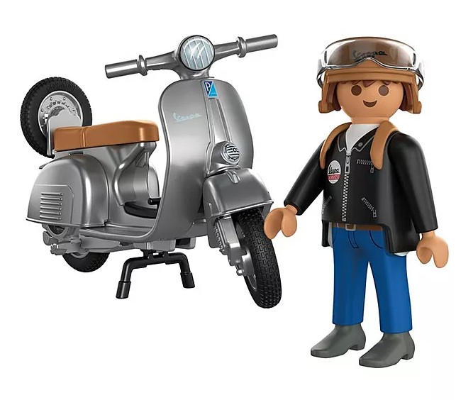 Eine Spielfigur in Lederjacke steht neben einem silbernen Spielzeug-Roller mit braunem Sitz.