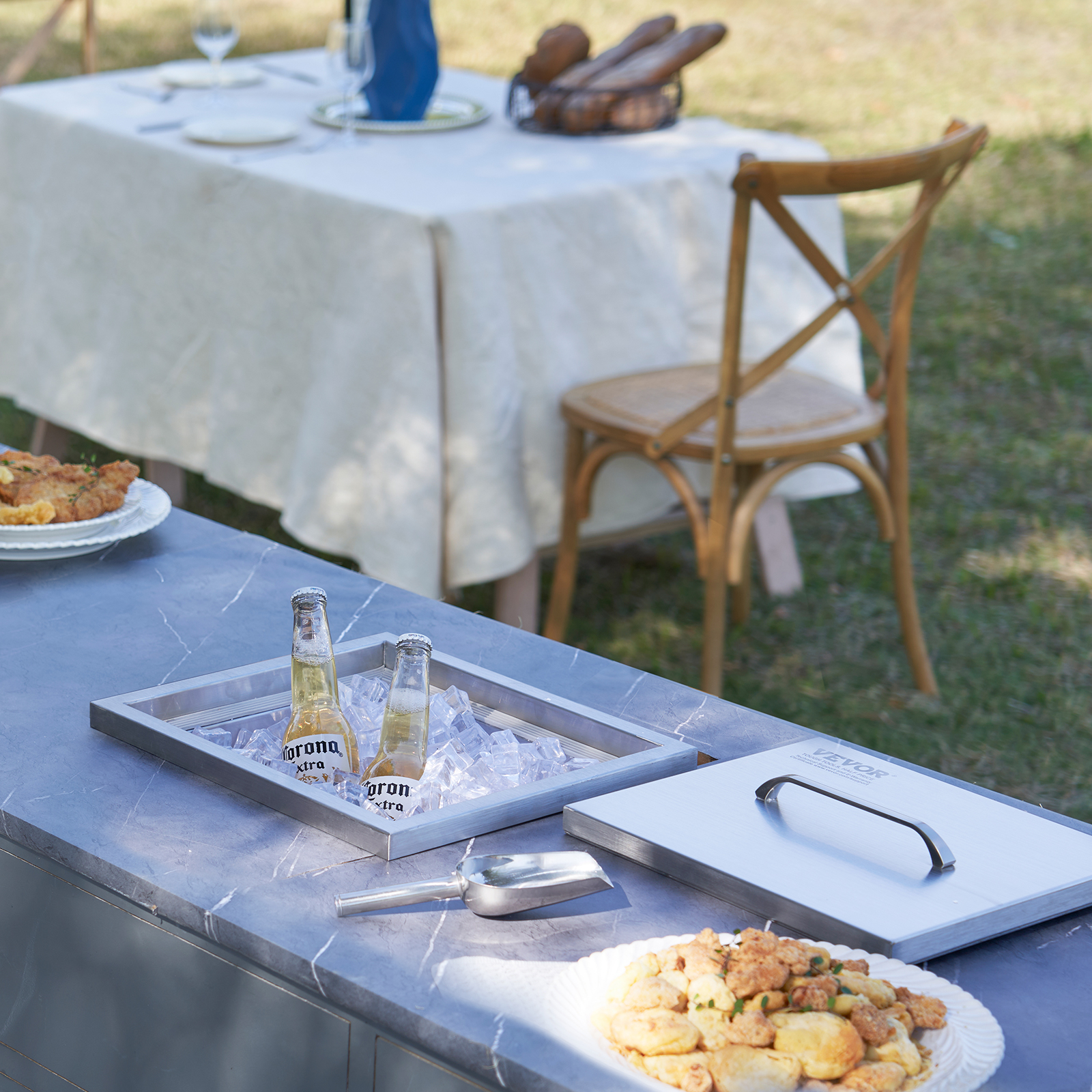 Botellas de cerveza Corona enfriándose en una hielera sobre una barra de mármol con comida, al aire libre.