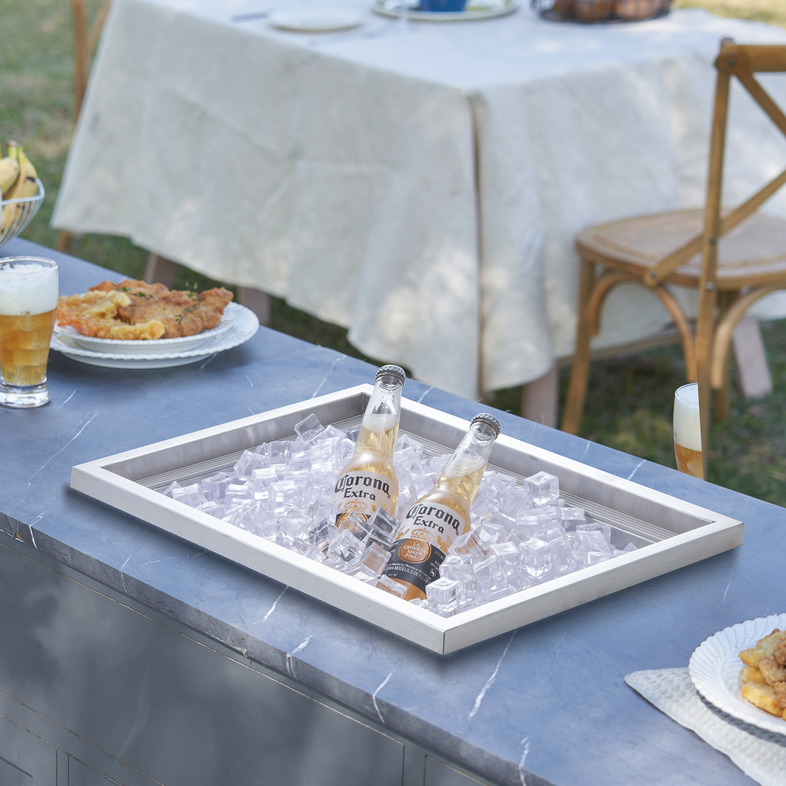 Dos botellas de cerveza Corona se enfrían en una bandeja de metal con hielo.
