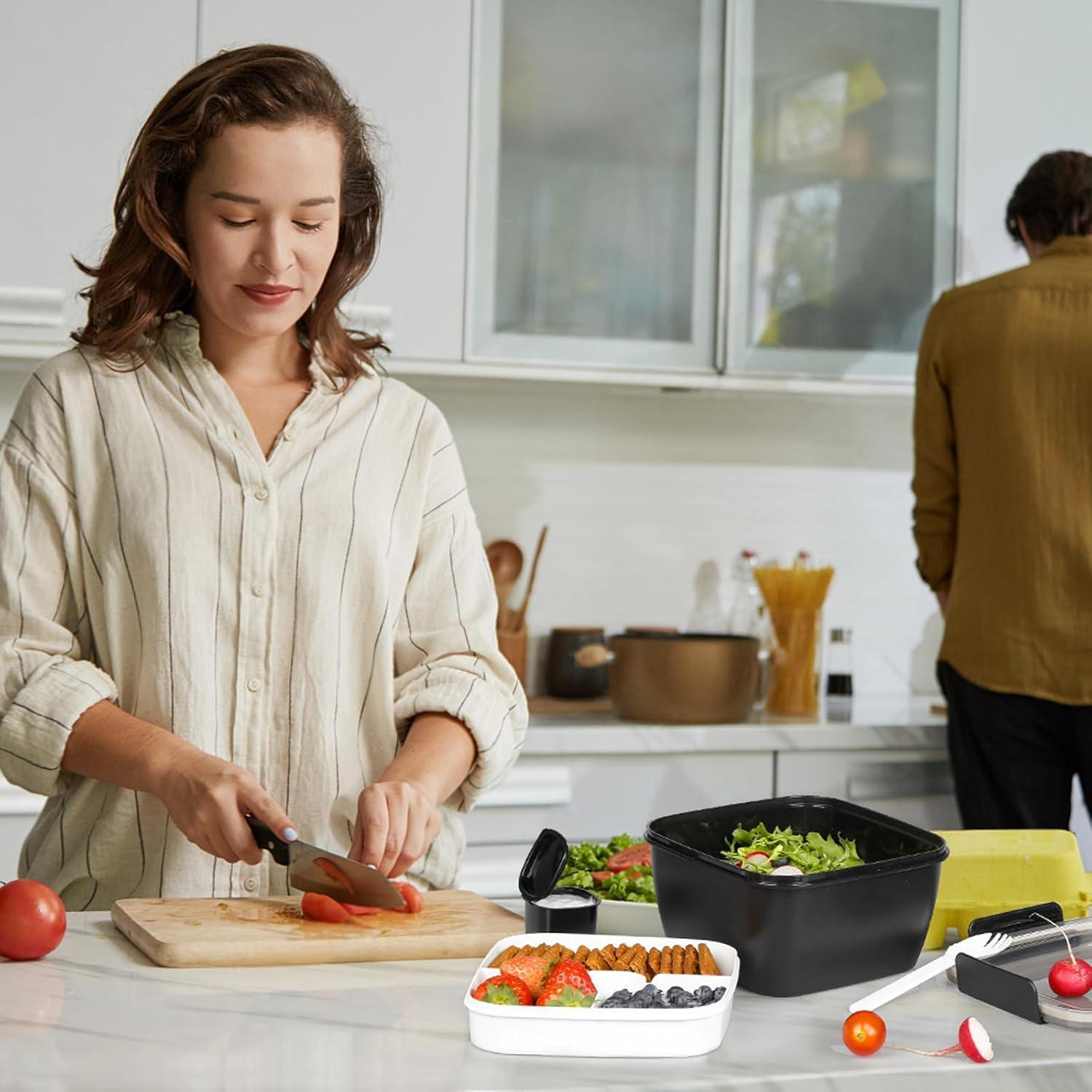 Una donna taglia i pomodori su un tagliere di legno in cucina mentre un uomo si trova sullo sfondo.