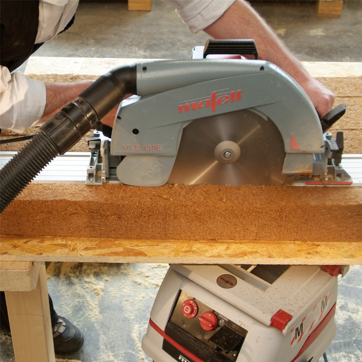 Handwerker sägt mit einer blauen Mafell Kreissäge Holz auf einer Werkbank.