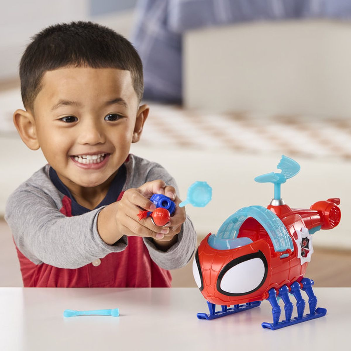 Un jeune garçon heureux joue avec un hélicoptère Spidey rouge.