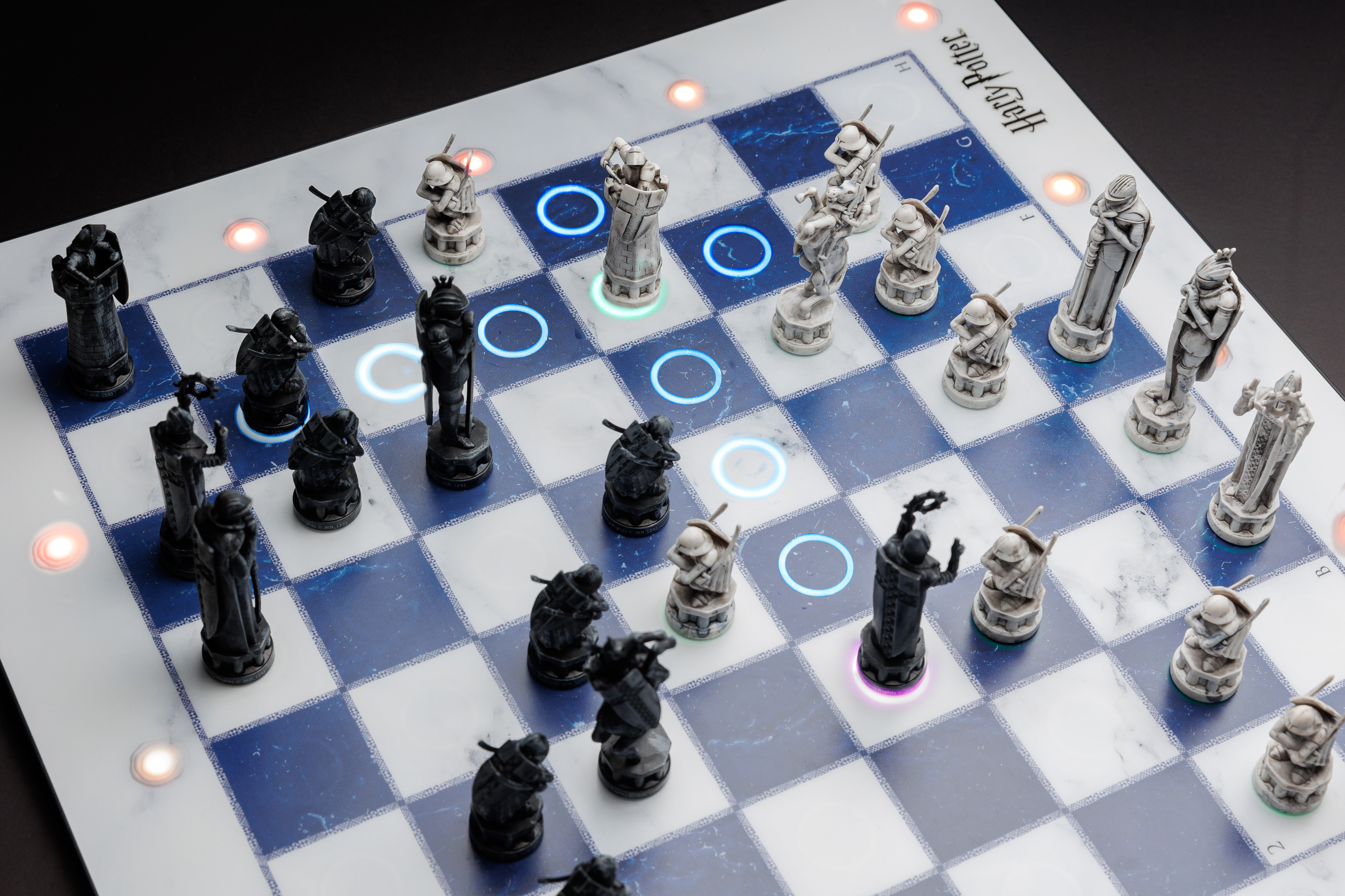 Un jeu d'échecs électronique Harry Potter avec plateau marbré et lumières bleues et oranges.
