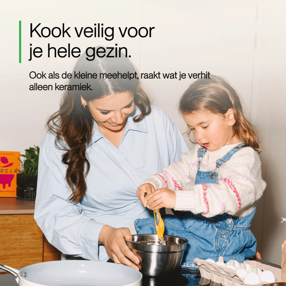 A woman and a young girl cook together in a kitchen, cracking an egg into a metal bowl.
