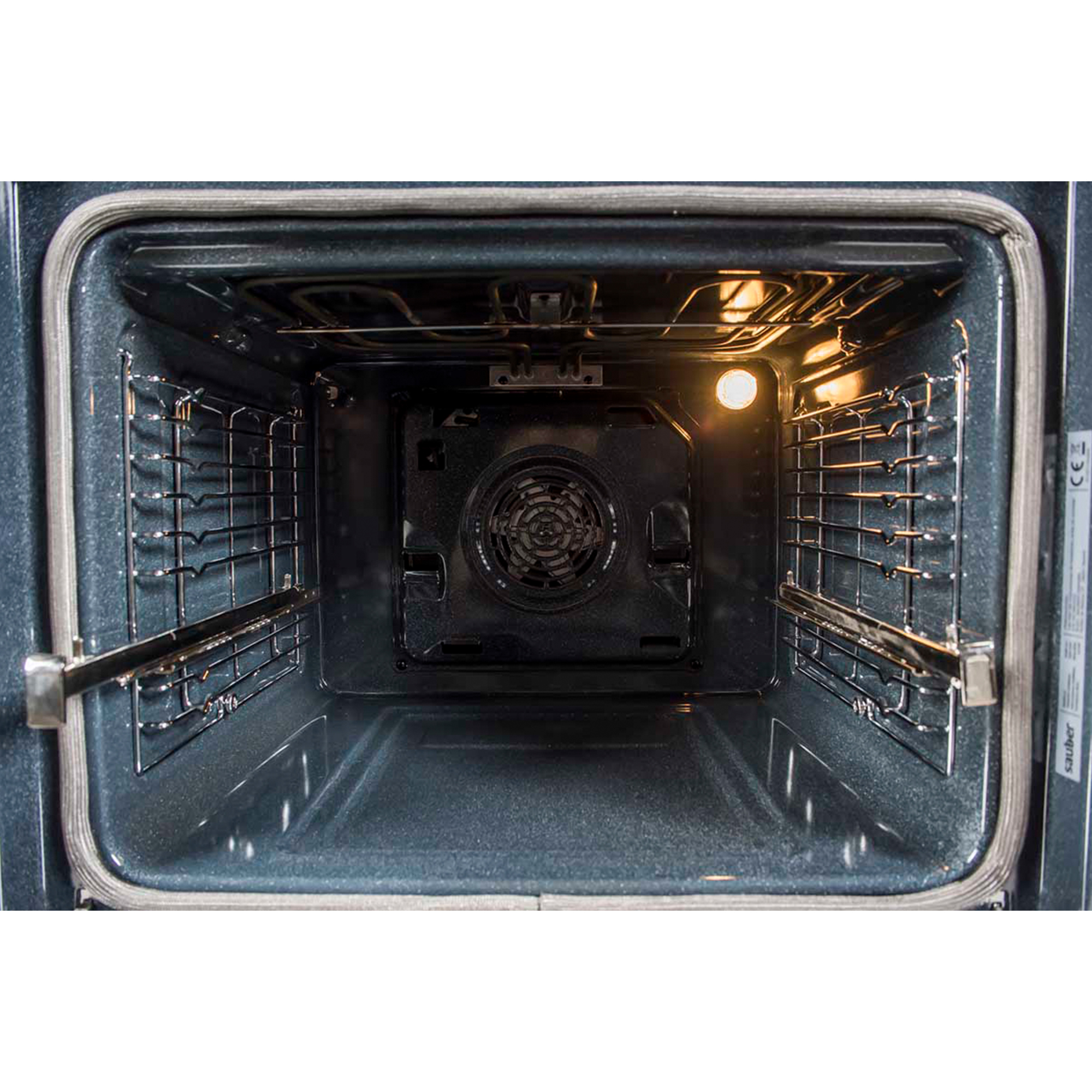 El interior de un horno vacío y limpio con rejillas laterales, un ventilador trasero e iluminación cálida.