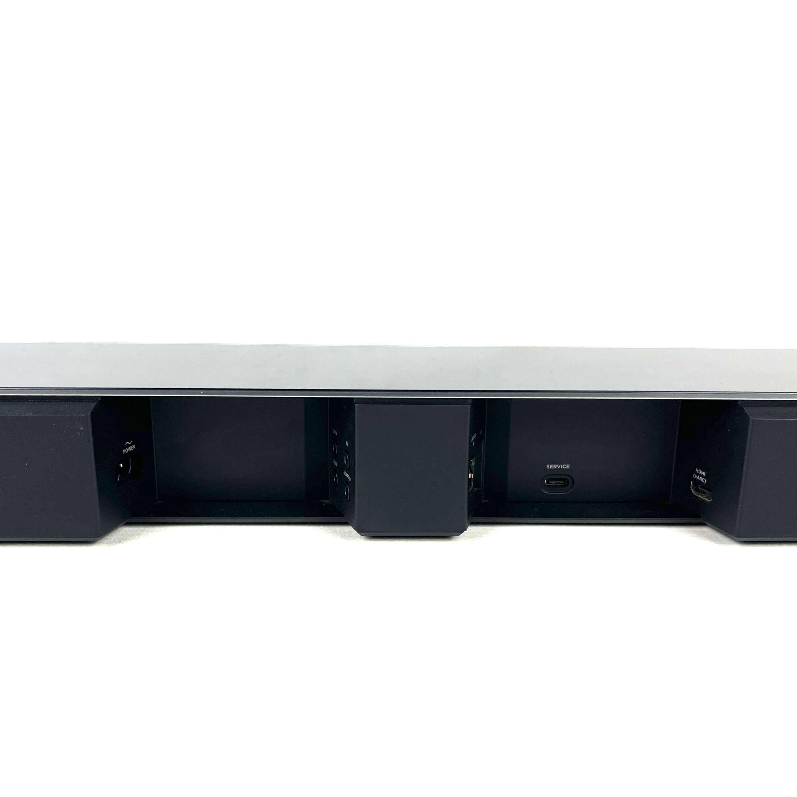 Vista posteriore di una soundbar nera, che mostra le porte di alimentazione, servizio e HDMI su sfondo bianco.